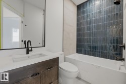 Bathroom featuring a modern vanity with a white countertop and dark wood-finish cabinetry, a recessed sink with a matte black faucet, and a large wall mirror - 