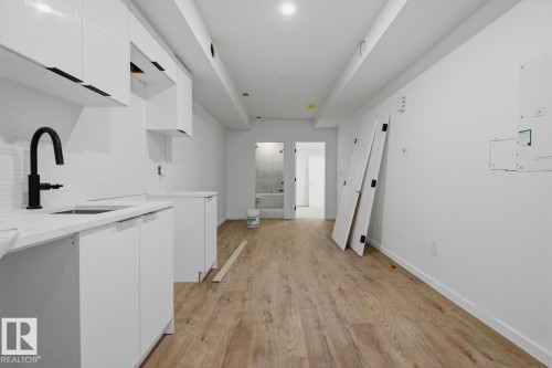 Contemporary kitchen area featuring white cabinetry, a white tile backsplash, and a matte black gooseneck faucet - 11327 122 Street, Edmonton, AB - Indoor Photo Showing Other Room