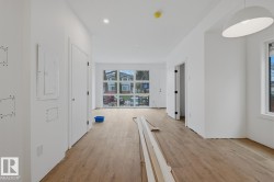 Open-concept living space featuring wood-finish flooring, recessed lighting, and expansive windows - 