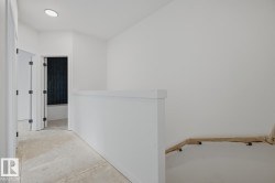 Upper-level hallway featuring a clean aesthetic with white walls and ceiling - 