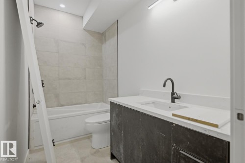 Contemporary bathroom featuring a dark vanity with integrated sink, matte black faucet, and white countertop - 11327 122 Street, Edmonton, AB - Indoor Photo Showing Bathroom