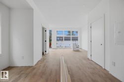 Open-concept living area featuring wood-finish flooring, recessed lighting, white walls, and a large multi-pane window - 