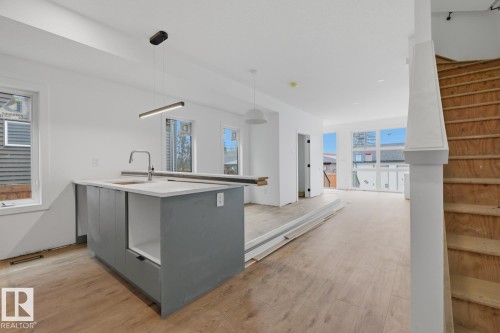 Open-concept kitchen featuring a central island with a sink and modern pendant lighting - 11327 122 Street, Edmonton, AB - Indoor