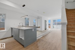 Open-concept kitchen featuring a central island with a sink and modern pendant lighting - 