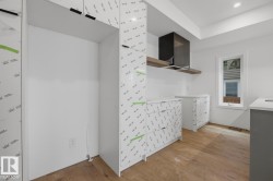 Modern kitchen space featuring wood-finish flooring, recessed lighting, and white walls - 