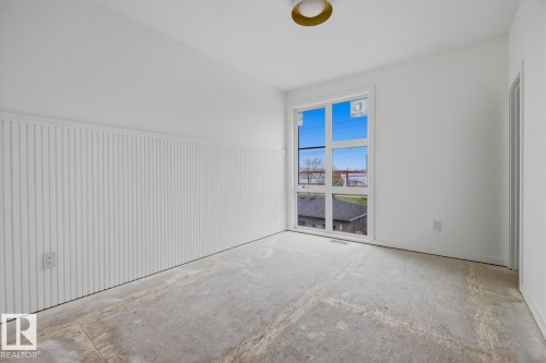 Room featuring a large multi-pane window, white walls, and a feature wall with vertical paneling - 11327 122 Street, Edmonton, AB - Indoor Photo Showing Other Room