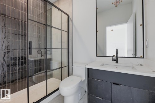Modern bathroom featuring a walk-in shower with black-framed glass enclosure and textured tile surround - 11327 122 Street, Edmonton, AB - Indoor Photo Showing Bathroom