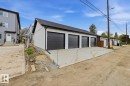 Multi-unit garage structure featuring four dark paneled garage doors, white siding, black trim, and a dark shingle roof - 11327 122 Street, Edmonton, AB  - Outdoor 