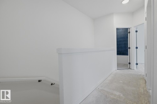 Hallway featuring a partial staircase, recessed lighting, and a doorway with dark blue subway tile - 11327 122 Street, Edmonton, AB - Indoor Photo Showing Other Room