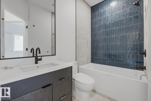 Bathroom featuring a dark blue vertical tile shower surround, matte black fixtures, a white soaking tub, and a vanity with a white countertop and integrated sink - 11327 122 Street, Edmonton, AB - Indoor Photo Showing Bathroom