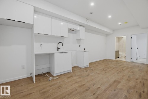 Open-concept living area featuring wood-finish flooring, recessed lighting, and a white kitchen with ample cabinetry - 11327 122 Street, Edmonton, AB - Indoor