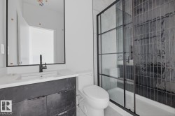 Bathroom featuring a black frame vanity mirror, dark wood-finish vanity, integrated sink with matte black faucet, and a black grid-style glass shower enclosure - 