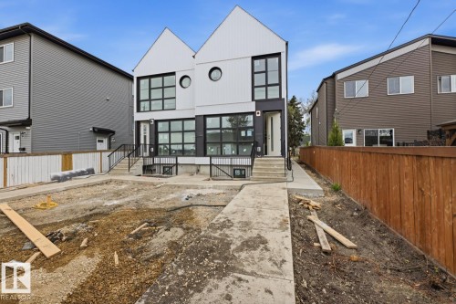 Modern duplex exterior featuring a contrasting white and dark facade with a prominent gabled roofline - 11327 122 Street, Edmonton, AB - Outdoor