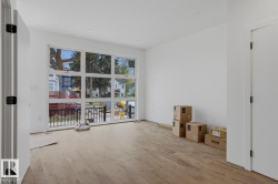 Expansive multi-pane window system, light wood-finish flooring, recessed ceiling lighting, crisp white walls, and a white interior door with black hardware - 
