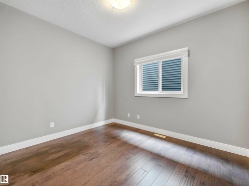 Room featuring light gray walls, white baseboards, and wood-finish flooring - 1090 Armitage Crescent, Edmonton, AB 