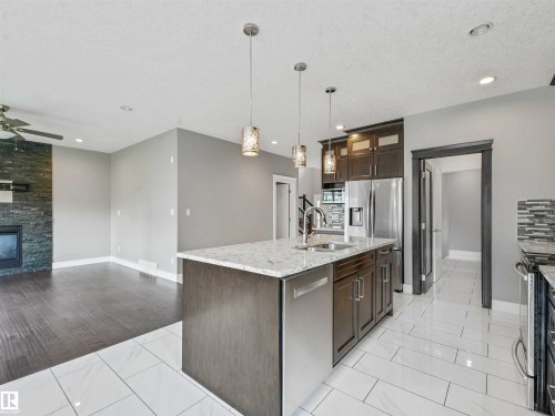 Modern kitchen island with a double basin sink, stainless steel appliances, and pendant lighting - 1090 Armitage Crescent, Edmonton, AB 