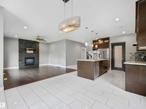 Open-concept living space featuring a kitchen island with pendant lighting, stainless steel appliances, and wood-finish cabinetry - 1090 Armitage Crescent, Edmonton, AB 
