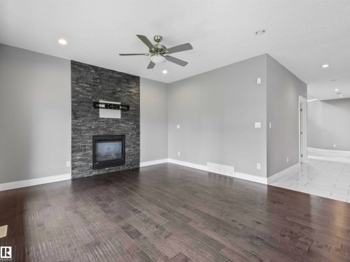 Living area featuring a floor-to-ceiling stacked stone fireplace, wood-finish flooring, a ceiling fan with integrated lighting, and recessed lighting - 1090 Armitage Crescent, Edmonton, AB 