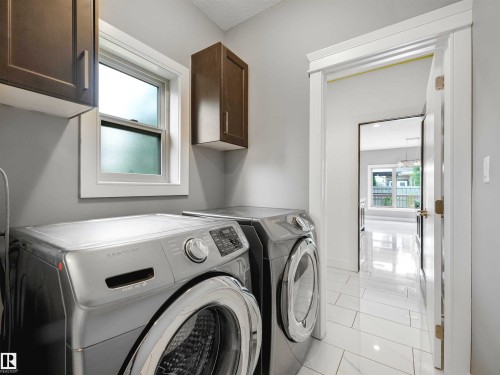 Laundry area featuring white tile flooring, upper cabinetry, and a window - 1090 Armitage Crescent, Edmonton, AB 