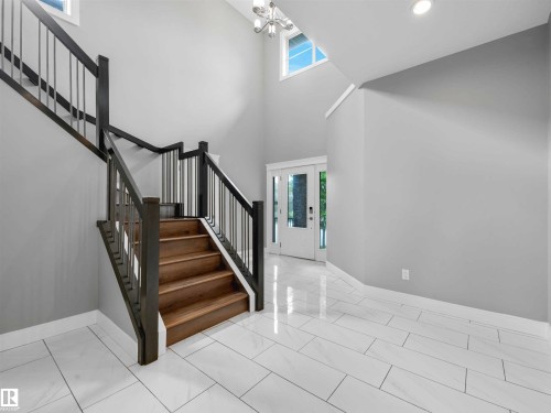 Foyer featuring a grand staircase with wood-finish treads and contemporary gray railings - 1090 Armitage Crescent, Edmonton, AB 