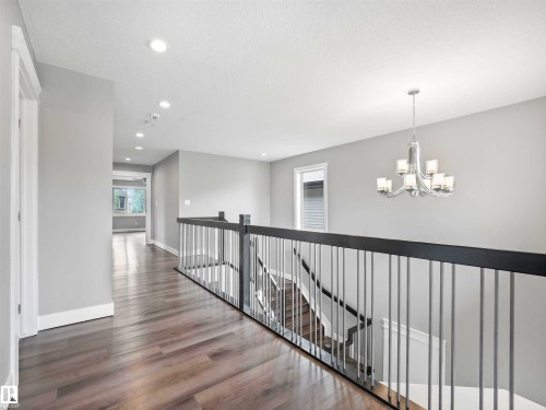 Upper-level hallway featuring wood-finish flooring, recessed lighting, and a contemporary chandelier - 1090 Armitage Crescent, Edmonton, AB 