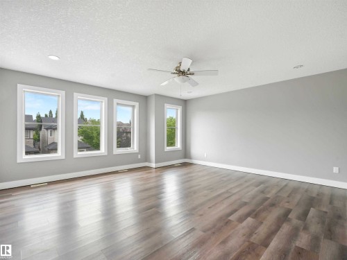 Spacious room featuring light wood-finish flooring, multiple windows with white trim, a ceiling fan with light fixture, and recessed lighting - 1090 Armitage Crescent, Edmonton, AB 