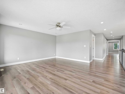 Spacious room featuring wood-finish flooring, light grey walls, and white trim - 1090 Armitage Crescent, Edmonton, AB 