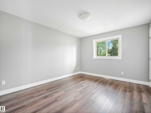 Bright room featuring a window with white trim, light gray walls, and wood-finish flooring - 1090 Armitage Crescent, Edmonton, AB 