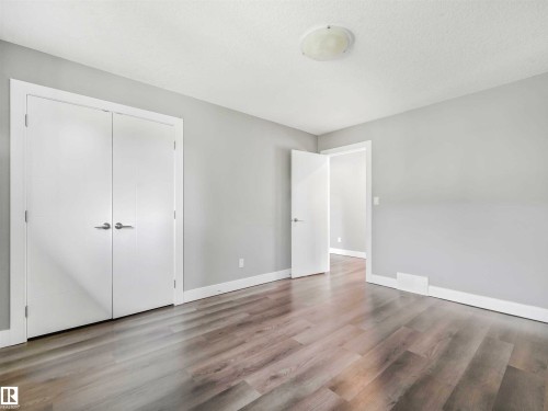 Room featuring light gray walls, wood-finish flooring, white baseboards, and a flush mount ceiling light - 1090 Armitage Crescent, Edmonton, AB 
