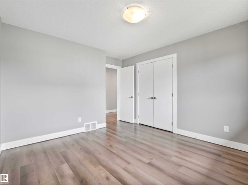 Spacious room featuring light wood-finish flooring, light gray walls, white baseboards, and a flush-mount ceiling light fixture - 1090 Armitage Crescent, Edmonton, AB 