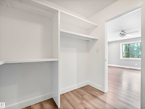 Built-in closet shelving with a hanging rod, light wood-finish flooring, and white baseboards - 1090 Armitage Crescent, Edmonton, AB 