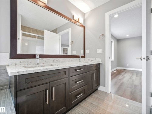 Dual vanity with a white countertop and undermount sinks, set upon dark gray cabinetry with brushed nickel hardware - 1090 Armitage Crescent, Edmonton, AB 