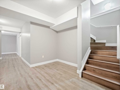 Staircase with wood-finish treads and risers, complemented by a white railing - 1090 Armitage Crescent, Edmonton, AB 