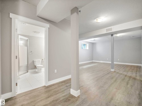Spacious room featuring wood-finish flooring, light gray walls, white trim, and recessed lighting - 1090 Armitage Crescent, Edmonton, AB 