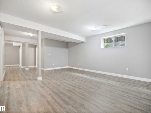 Spacious room featuring light grey walls, wood-finish flooring, and white trim - 1090 Armitage Crescent, Edmonton, AB 