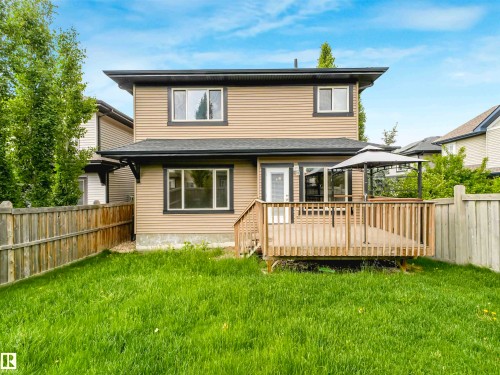 Rear exterior featuring a spacious wood deck, privacy fencing, and a manicured lawn - 1090 Armitage Crescent, Edmonton, AB 