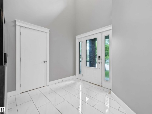 Foyer featuring a double entry door with clear glass panels, a single interior door, high ceilings, and white tile flooring - 1090 Armitage Crescent, Edmonton, AB 