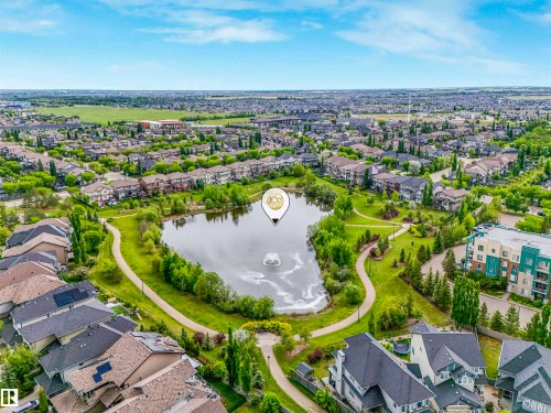 Aerial perspective showcasing a residential area with a prominent central pond featuring a water fountain - 1090 Armitage Crescent, Edmonton, AB 