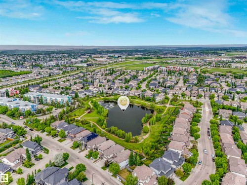 Aerial perspective showcasing a developed neighborhood with residential properties, commercial structures, and a central pond feature - 1090 Armitage Crescent, Edmonton, AB 