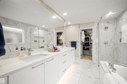 Contemporary bathroom featuring a dual vanity with white cabinetry, integrated sinks, and polished chrome fixtures - 
