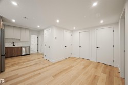 Open-concept living area with wood-finish flooring, recessed lighting, and multiple white panel doors - 