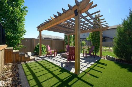 Outdoor pergola with a paved patio area, surrounded by artificial turf and mature landscaping - 12171 177 Avenue, Edmonton, AB 