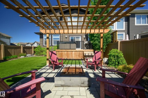 Backyard patio featuring a wood pergola over paver stones, a built-in fire pit, and a manicured lawn - 12171 177 Avenue, Edmonton, AB 