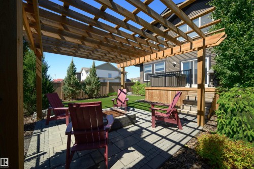 Expansive outdoor patio with a wooden pergola, paver stone hardscaping, built-in fire pit, and a manicured lawn - 12171 177 Avenue, Edmonton, AB 