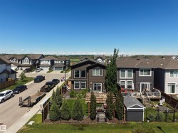 Modern two-story residence featuring a dark brown exterior with white trim windows and a fenced backyard - 