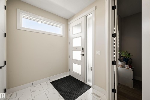 Modern entry featuring a contemporary multi-paneled door with opaque glass, a side lite, and matte black hardware - 12171 177 Avenue, Edmonton, AB 