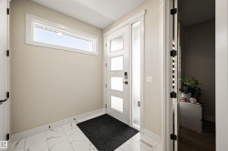 Modern entry featuring a contemporary multi-paneled door with opaque glass, a side lite, and matte black hardware - 