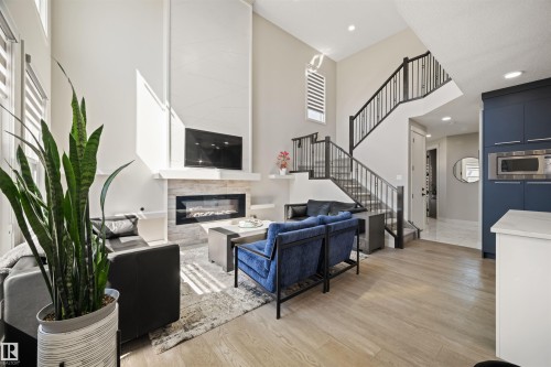 Spacious living area featuring high ceilings, wood-finish flooring, and a modern fireplace with stone surround - 12171 177 Avenue, Edmonton, AB 