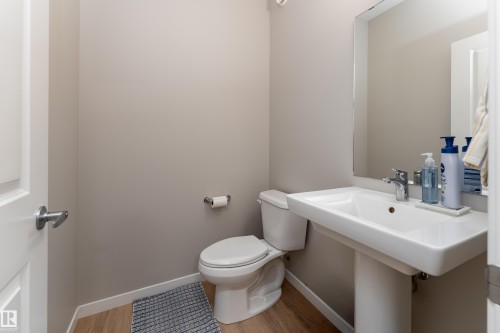 Bathroom featuring a white pedestal sink, mirror, and wood-finish laminate flooring - 2520 152 Avenue, Edmonton, AB 