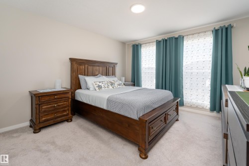 Bedroom featuring light neutral wall paint, light-colored carpeting, two large windows with privacy blinds, and a flush-mount ceiling light fixture - 2520 152 Avenue, Edmonton, AB 